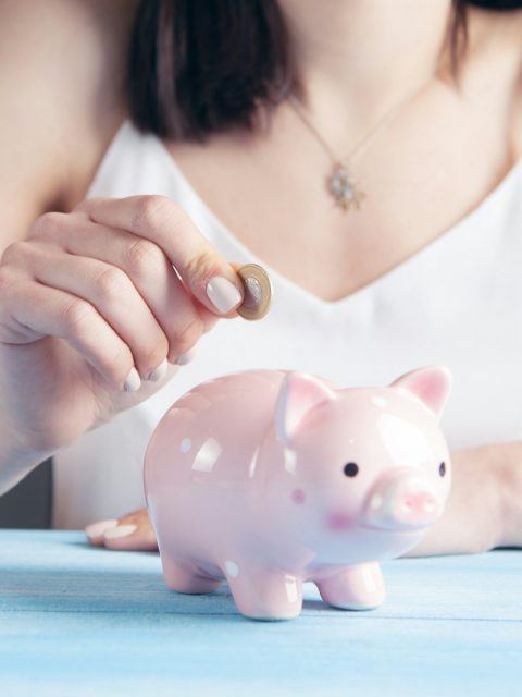 woman in white tank top holding pink pig figurine