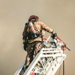 A fireman climbing up the ladder of a fire truck
