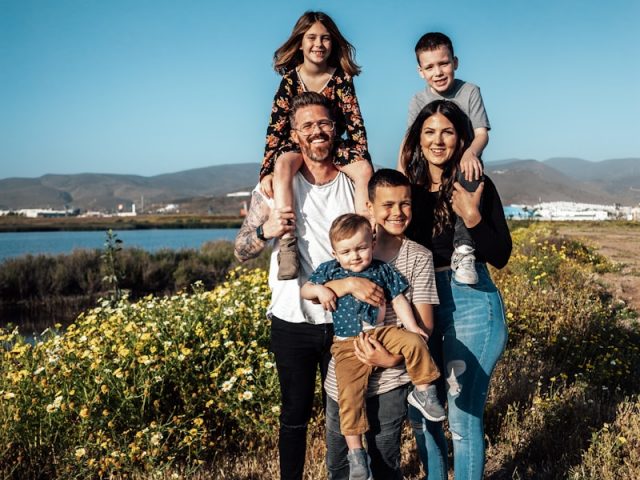 2 women and man standing on green grass field during daytime